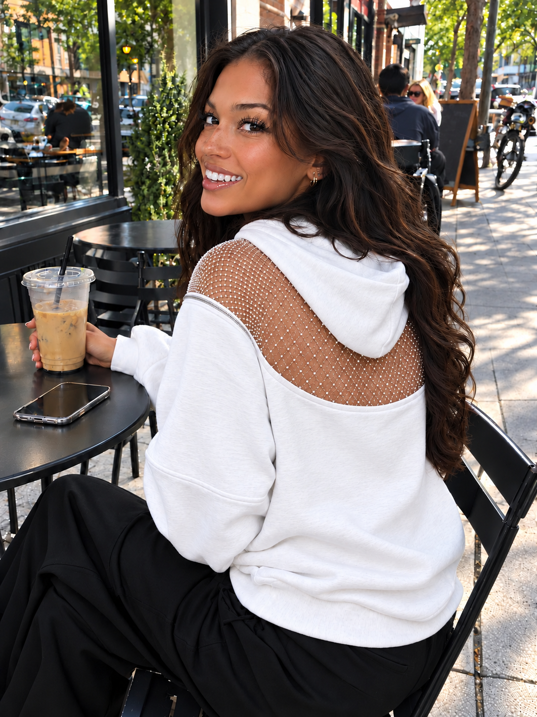 White Backless Hoodie mesh-back detail at an outdoor café.