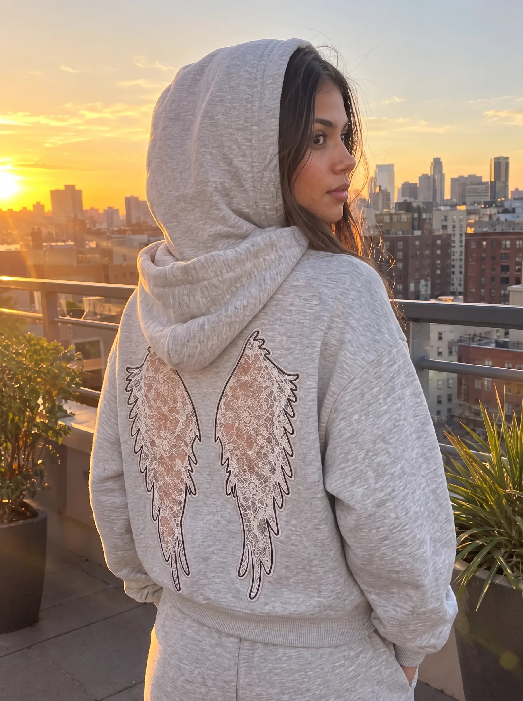Heather Grey Laced Wing Hoodie on a rooftop at sunset, model looking back over her shoulder.